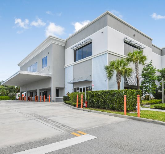Modern white self-storage facility exterior with drive-up access and landscaping.