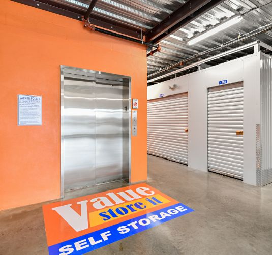 Value Store It self-storage facility entrance with elevator and orange branding signage.