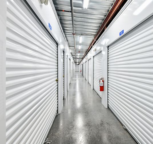 Interior hallway of climate-controlled storage units with white roll-up doors.