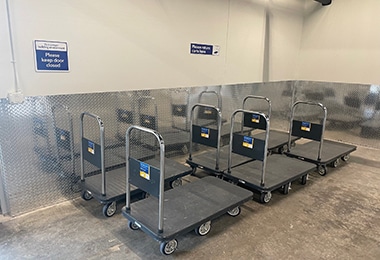 Row of platform hand trucks lined up indoors, Value Store It facility.