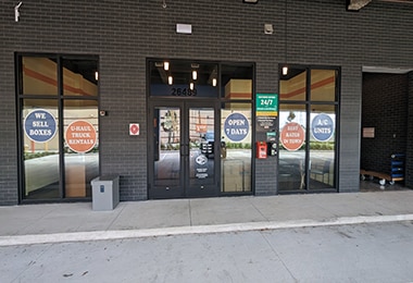 Value Store It storefront entrance with glass doors and windows, brick facade, daytime.