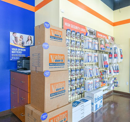 Value Store It interior with branded storage boxes, security signage, and retail display shelving.