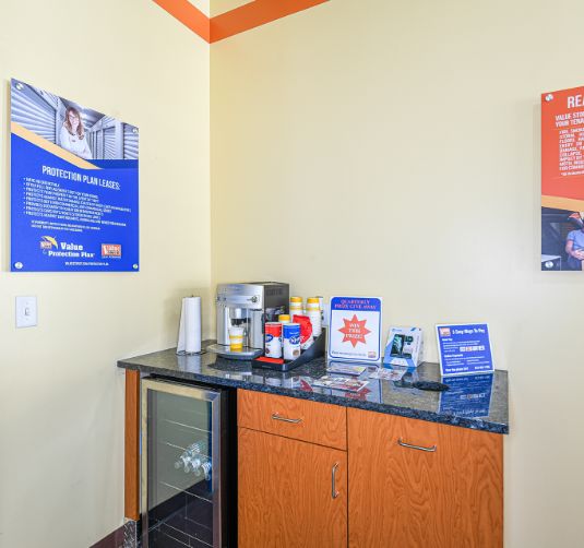 Interior break room corner with storage cabinet, refrigerator, and informational posters at Value Store It facility.