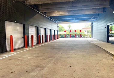 Interior of climate-controlled storage facility with multiple red-door units and concrete flooring.